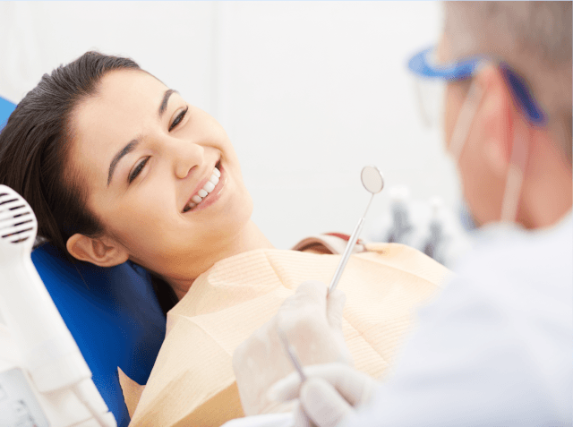 Dental patient reclined in a chair smiling at the hygienist.